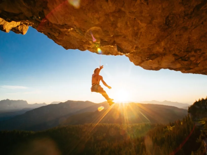 Mann hängt am Kletterseil an einem Felsen
