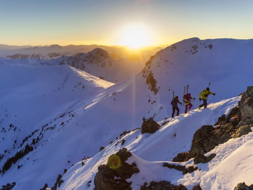 Drei Skitourengeher wandern auf einen schneebedeckten Gipfel