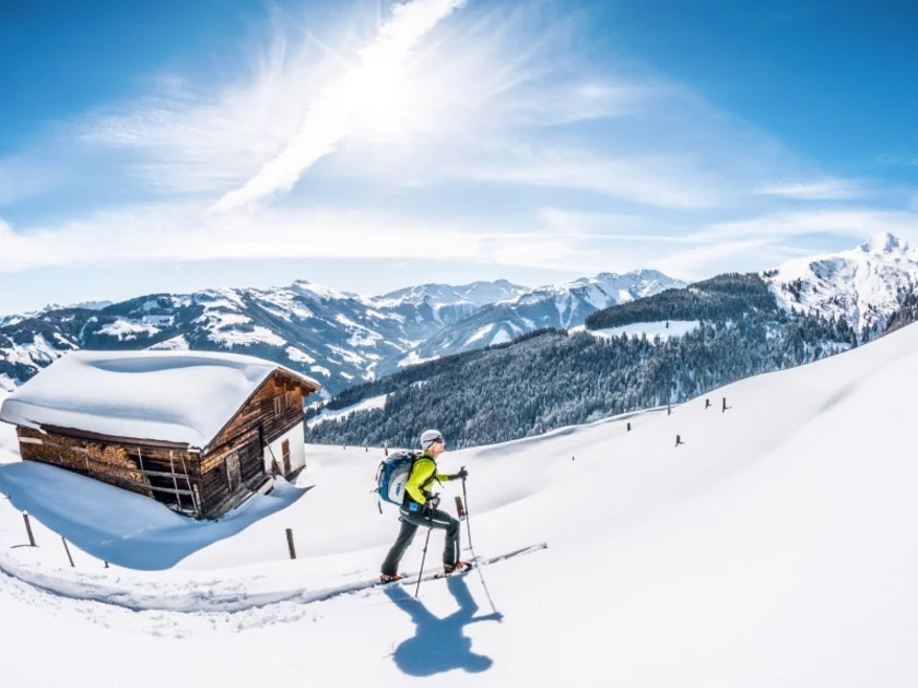 Ein Skitourengeher geht im Tiefschnee bei einer Hütte vorbei